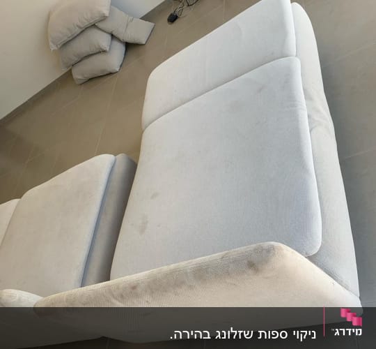 ספה מלוכלכת על רצפה עם כריות בצד